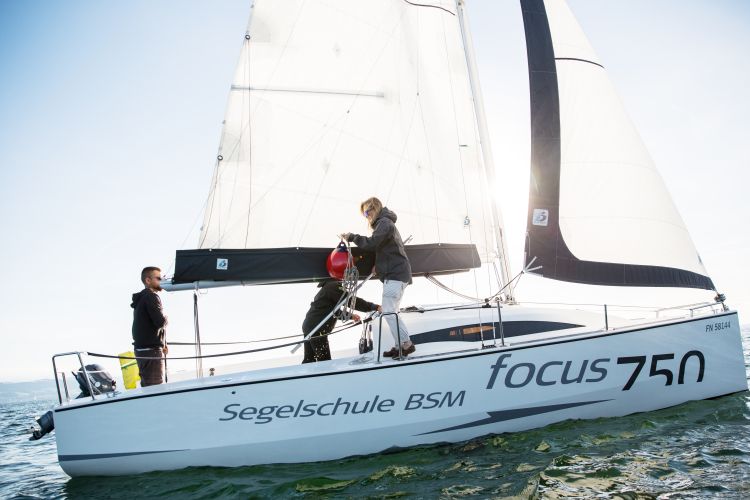 Segelschiff mit drei Personen wobei eine Person eine Tripp Boje in der Hand hat